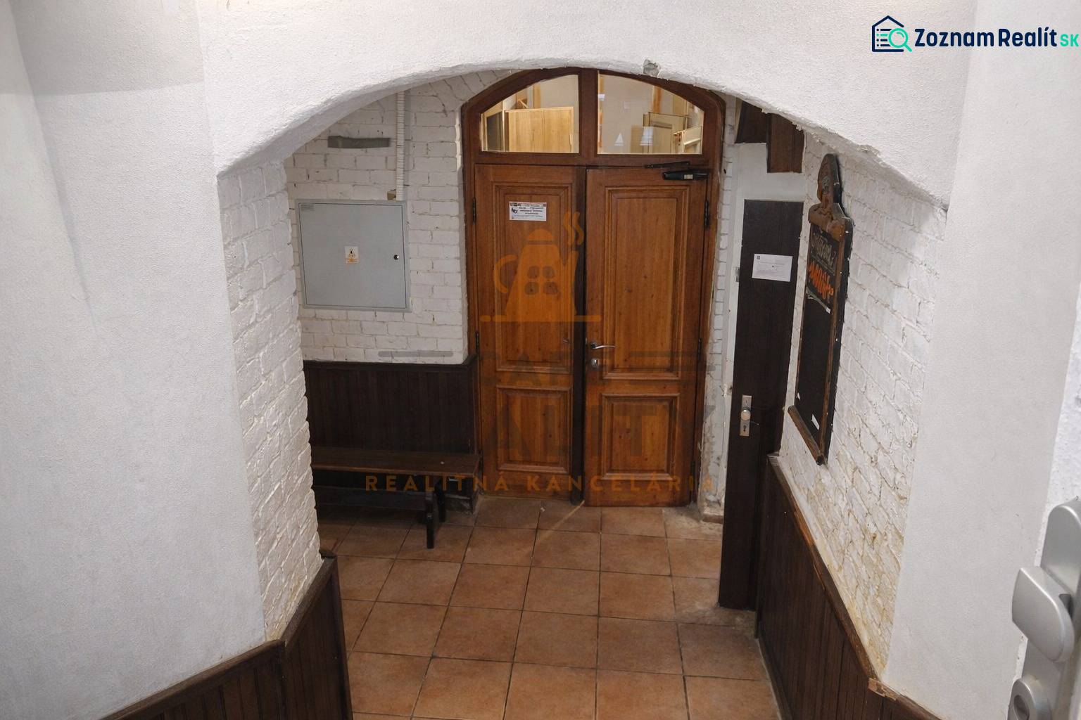 Bejárati ajtó üzlethelyiségben téglafallal és csempézett padlóval.