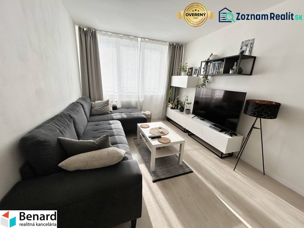 Nappali egy kétszobás lakásban fa mintázatú padlóval és kanapéval.