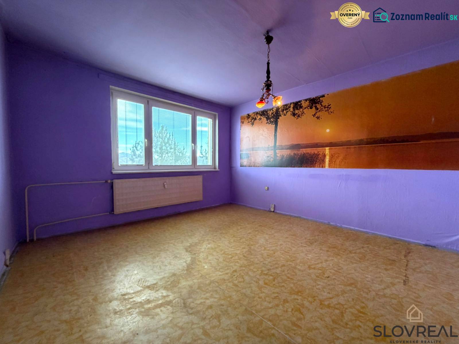 Lila színű szoba egy kétszobás lakásban, fa dekorációjú padlóval és nagy ablakkal.