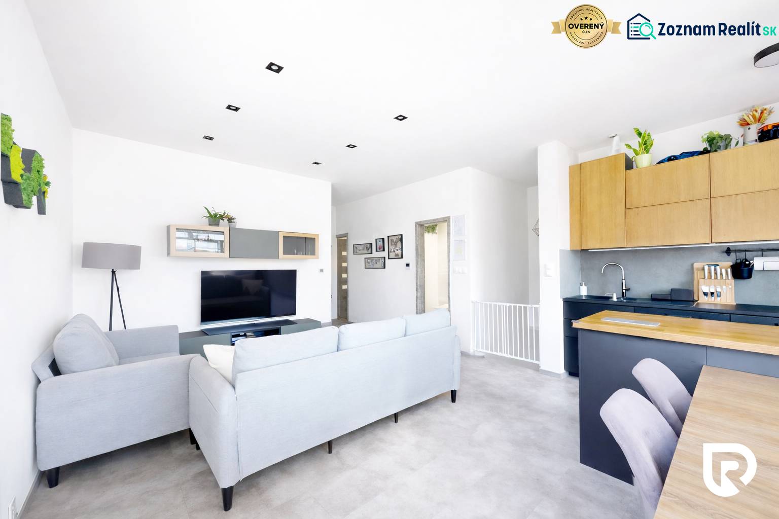 Világos nappali egy háromszobás lakásban kényelmes kanapéval és televízióval.