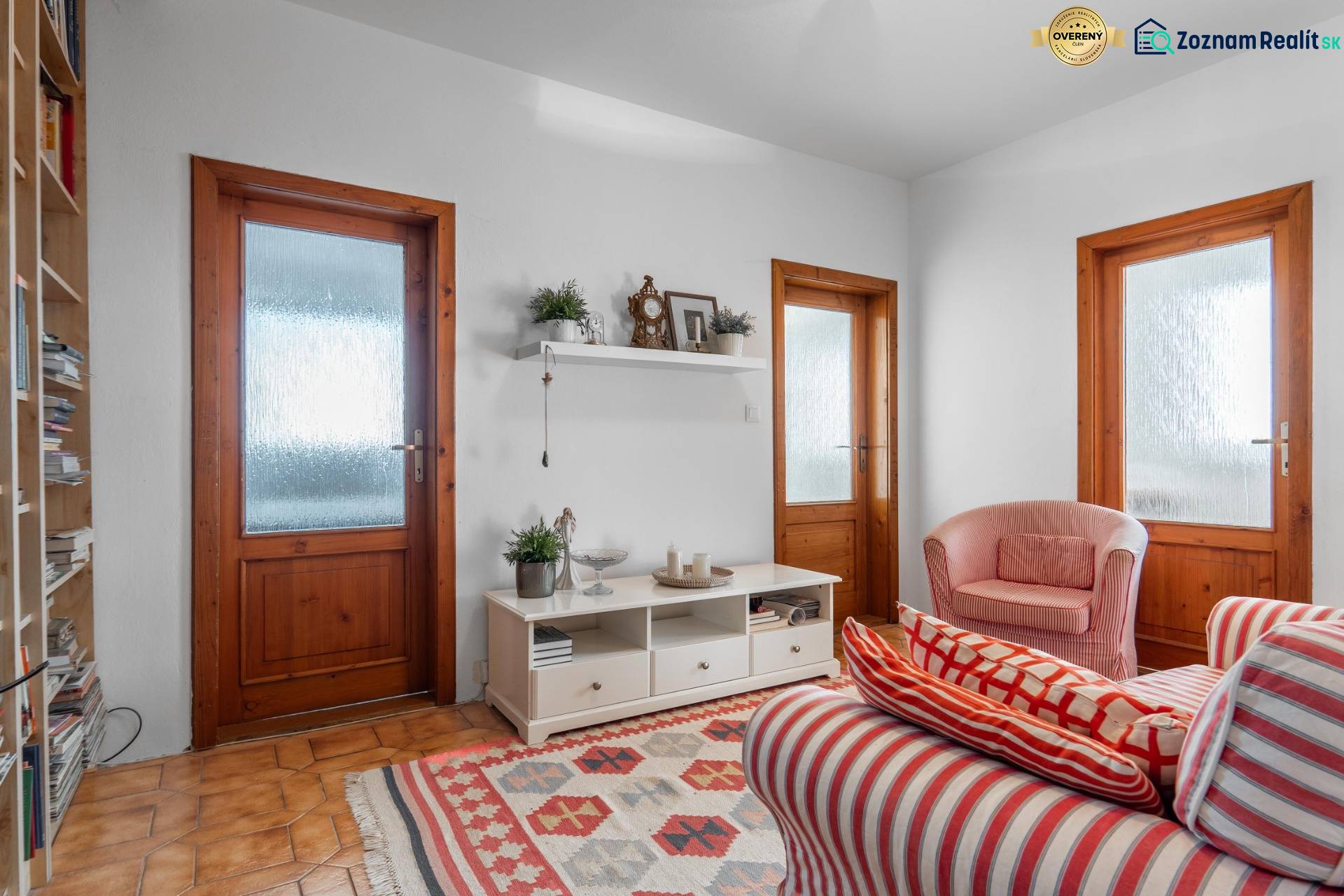 Nappali egy négy szobás lakásban piros csíkos fotelekkel és falra szerelt polccal.