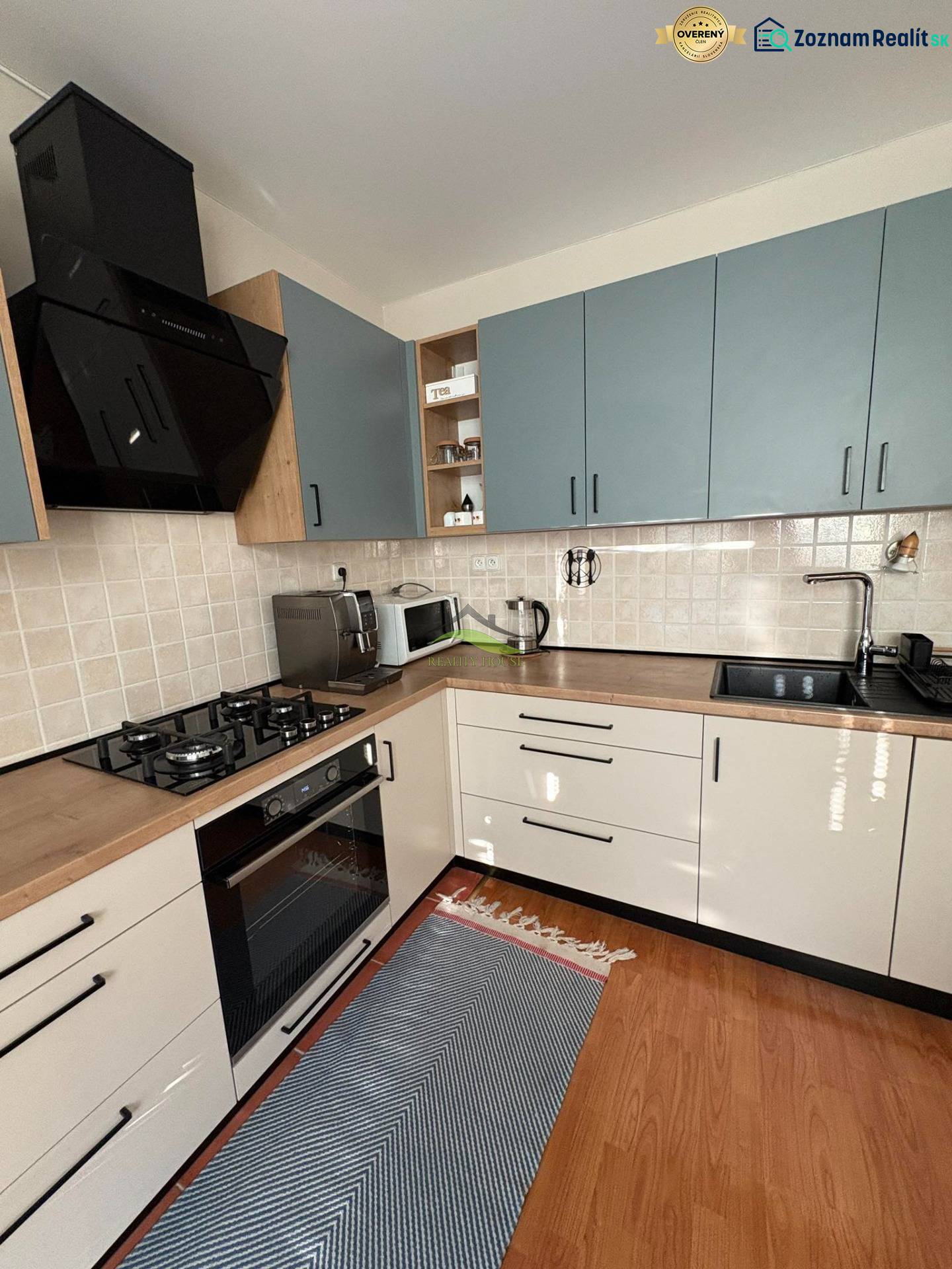 Konyha egy háromszobás lakásban csempézett burkolattal és fa mintázatú padlóval.