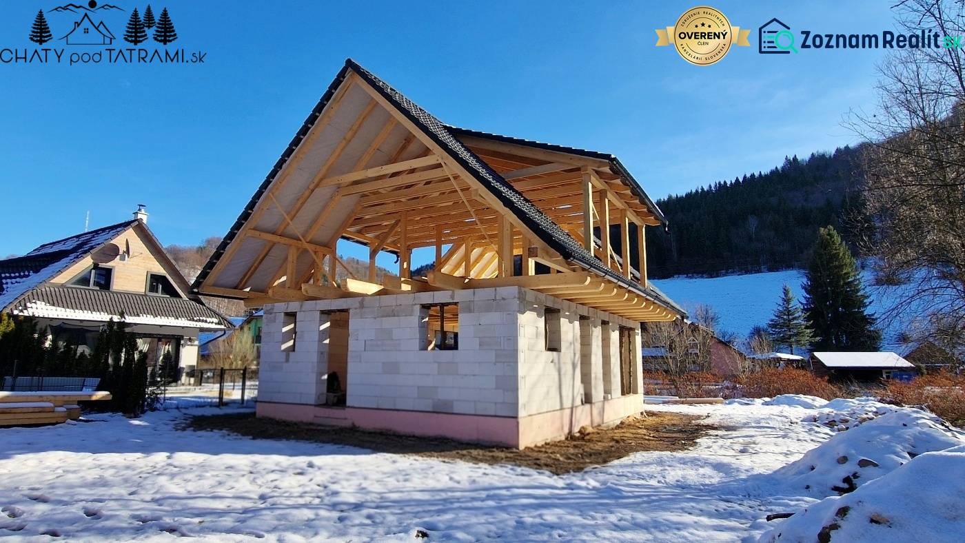 Faház építése Mýte pod Ďumbierom téli tájban, fa szerkezettel.