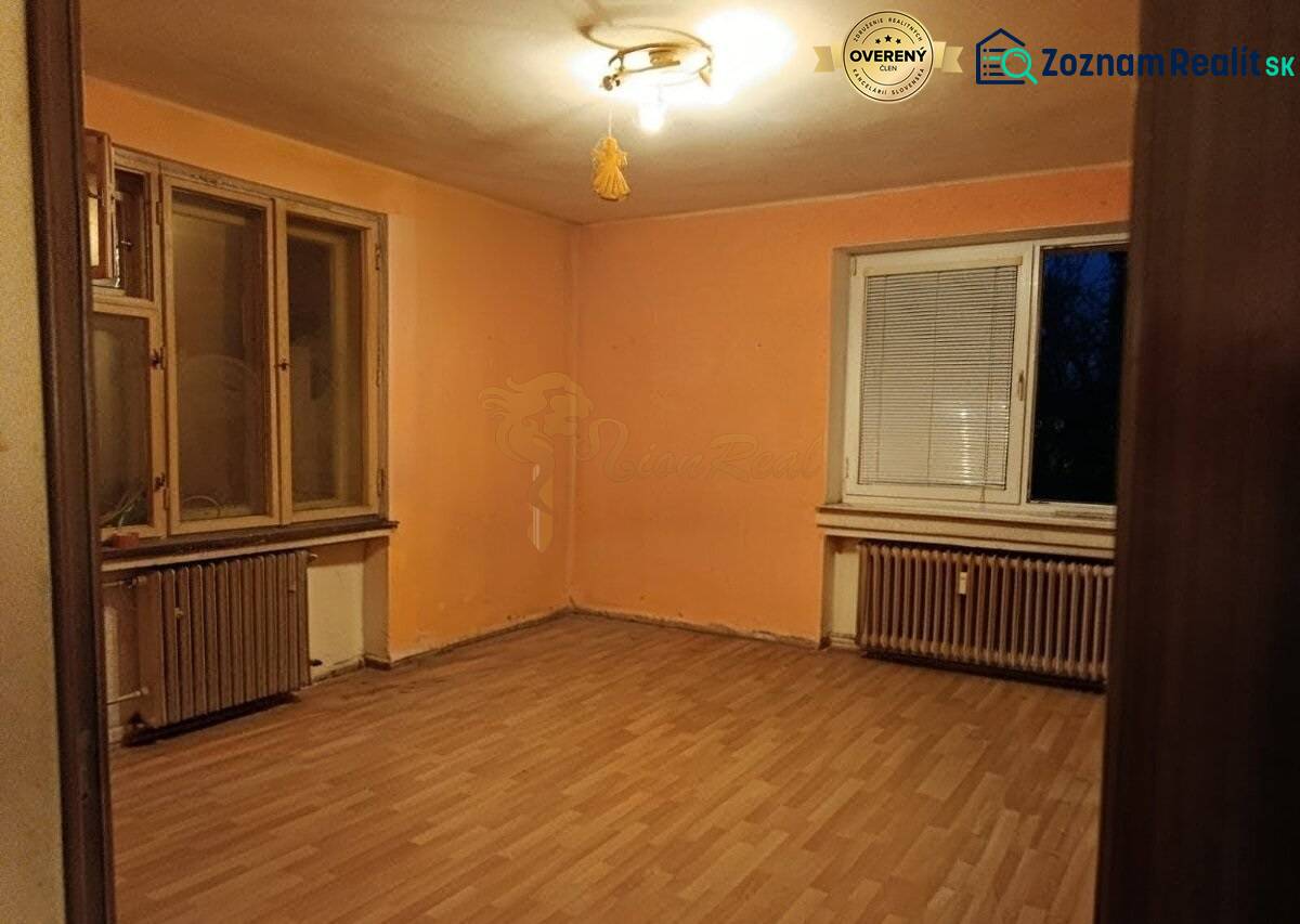 Szoba egy kétszobás lakásban, narancssárga falak, fa dekoros padló, radiátorok.