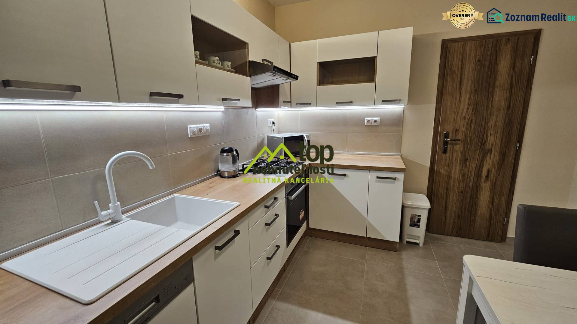 Konyha egy kétszobás lakásban fehér szekrényekkel és fa dekor padlóval.