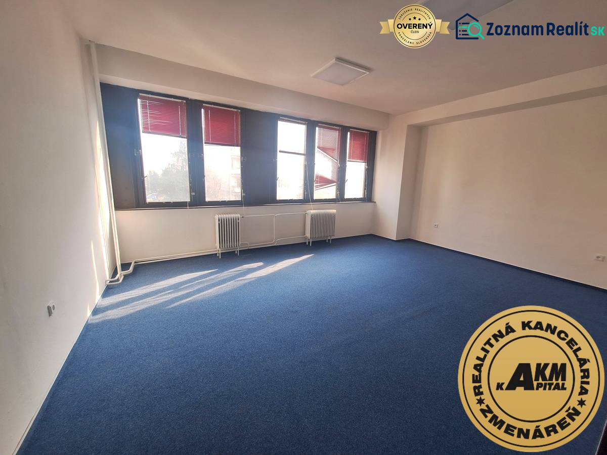 Iroda kék szőnyeggel és nagy ablakokkal, világos tér.