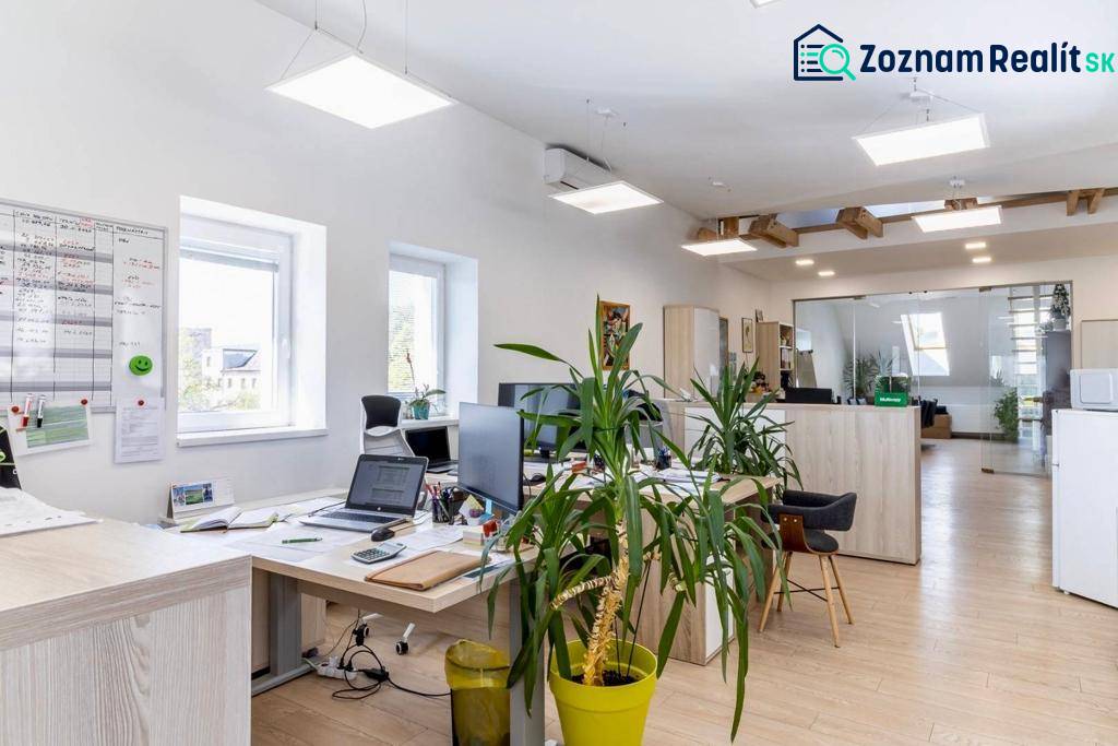 Világos irodák számítógépekkel, növényekkel és fa dekorációjú padlóval.