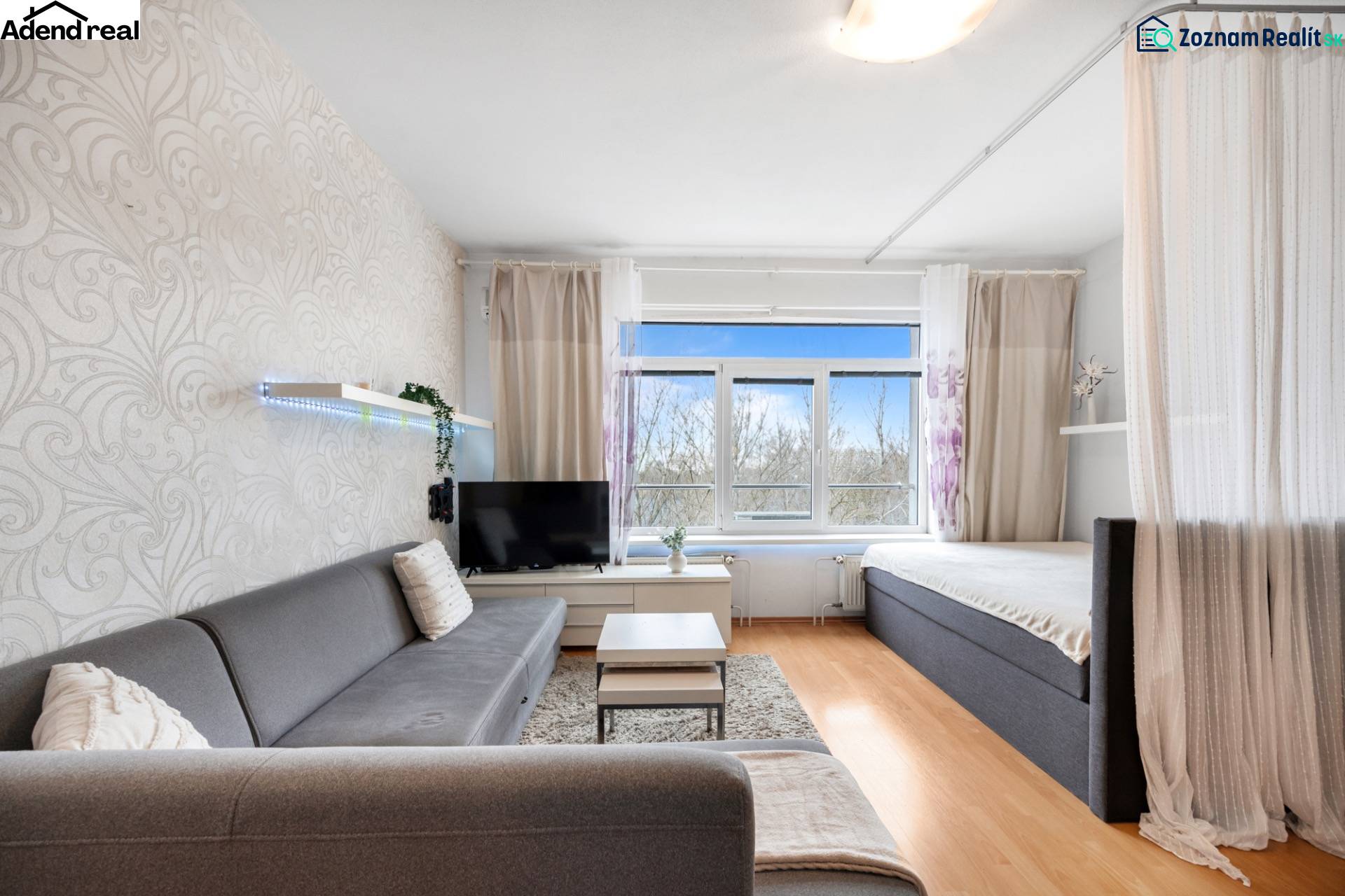 Nappali kanapéval, függönnyel és televízióval, fa dekorációjú padlóval.