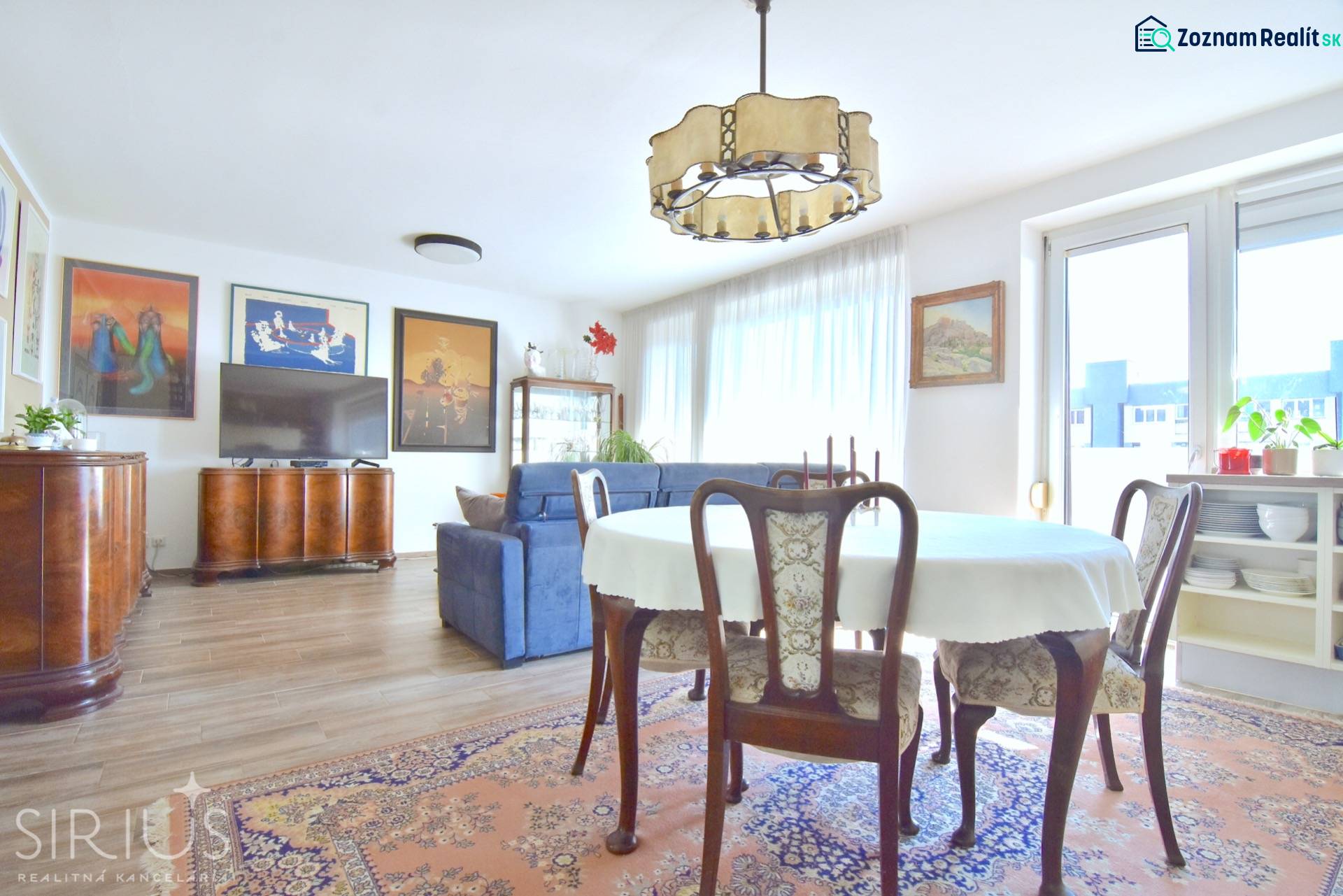 Nappali étkezőasztallal, kanapéval és fa dekorációjú padlóval egy háromszobás lakásban.