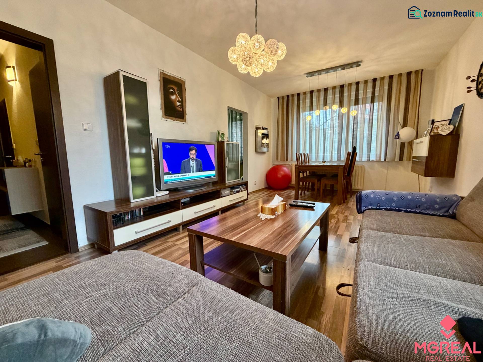 Nappali egy háromszobás lakásban, fa mintázatú padlóval és kényelmes kanapéval.