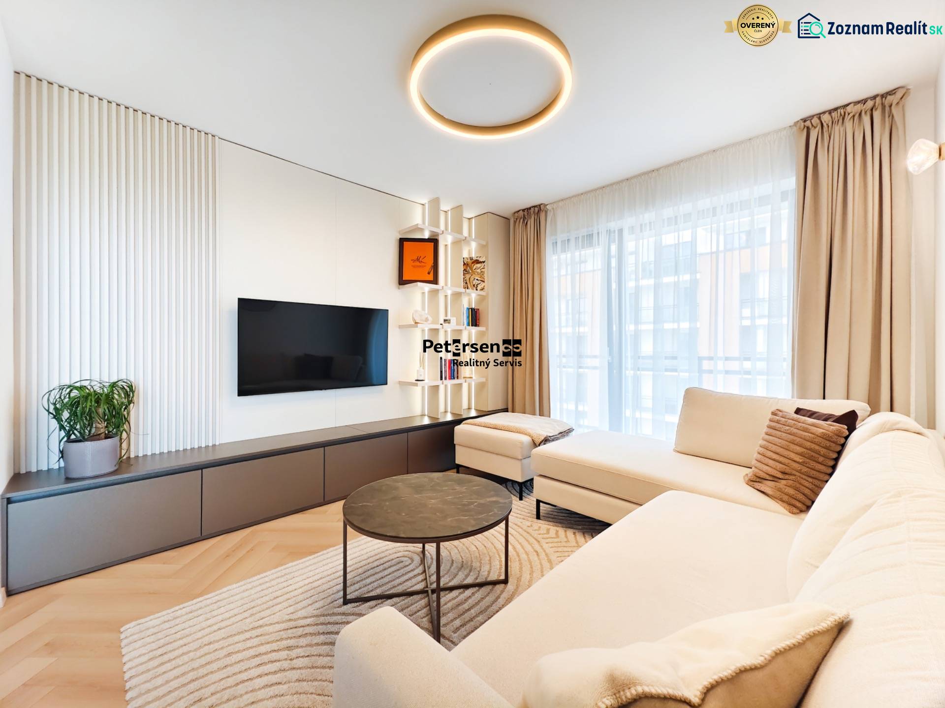 Nappali egy kétszobás lakásban kanapéval, televízióval és fa dekorációjú padlóval.