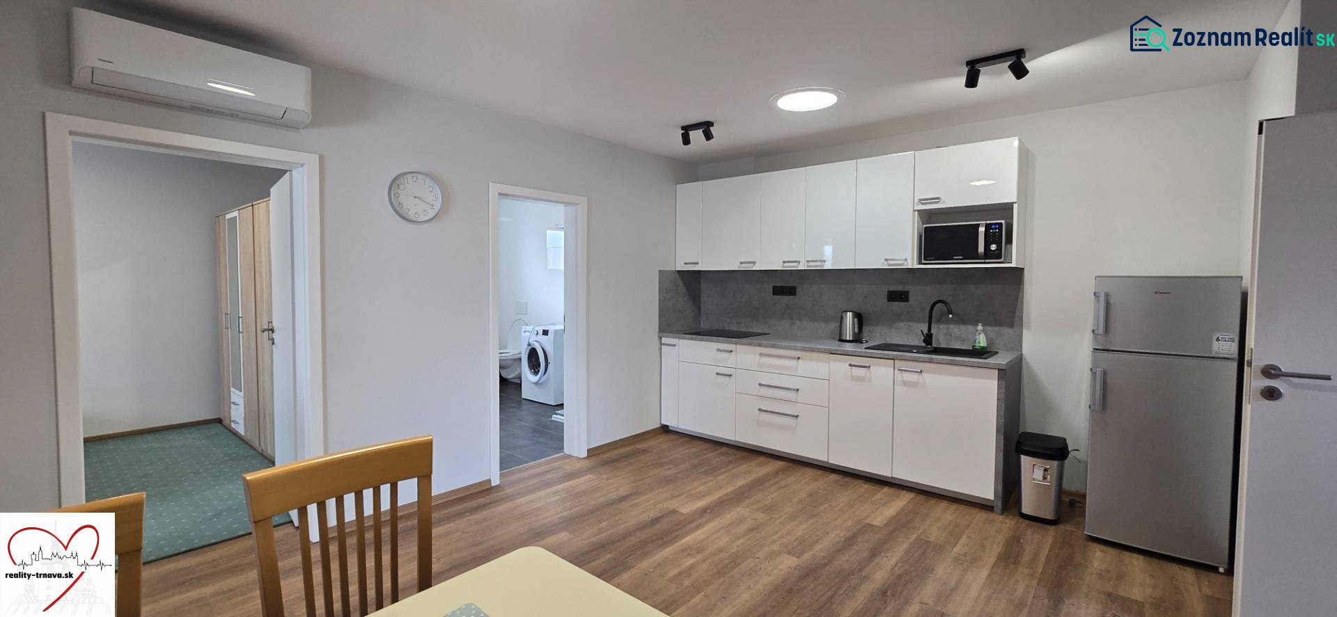 Konyha fehér szekrényekkel és készülékekkel egy háromszobás lakásban, fa dekor padlóval.