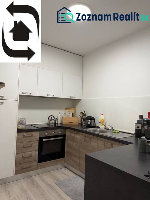 Konyha egy kétszobás lakásban, fa hatású padlóval és fehér szekrényekkel.