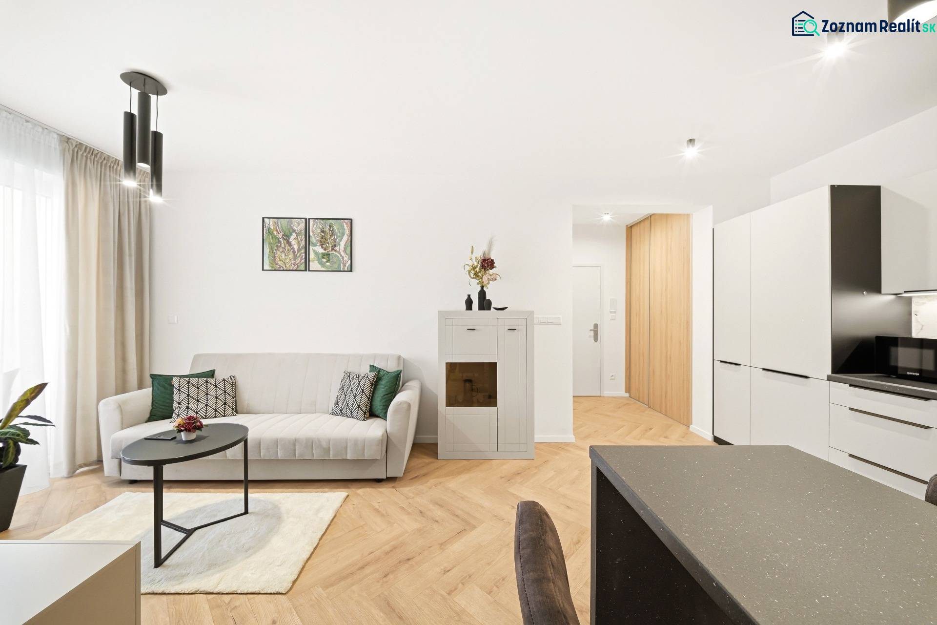 Nappali egy négy szobás lakásban fehér kanapéval és fa mintázatú padlóval.