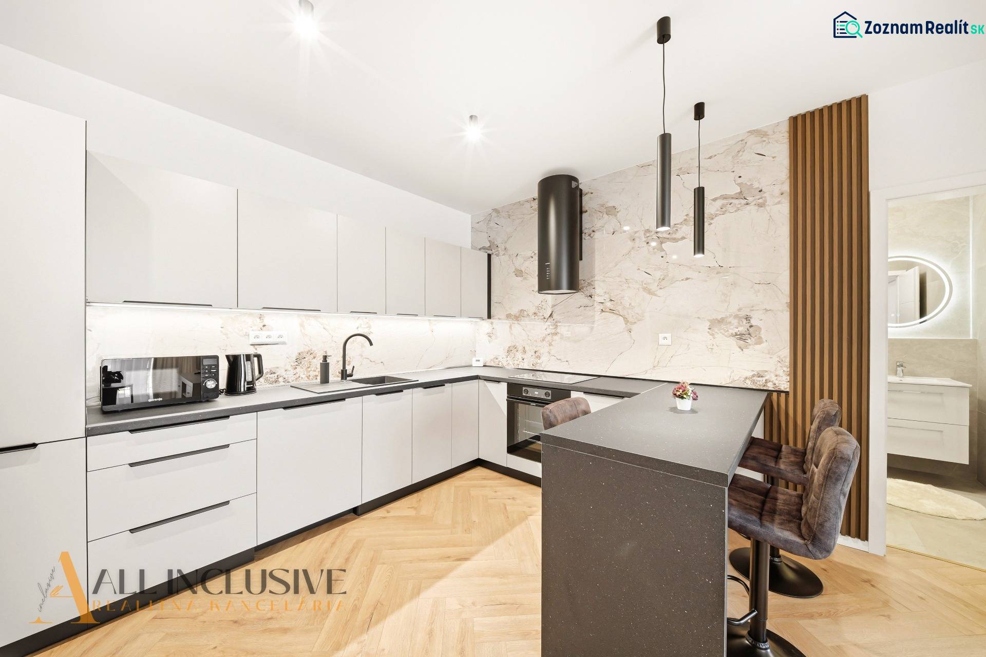 Konyha fehér szekrényekkel, szigettel és fa hatású padlóval egy 4 szobás lakásban.