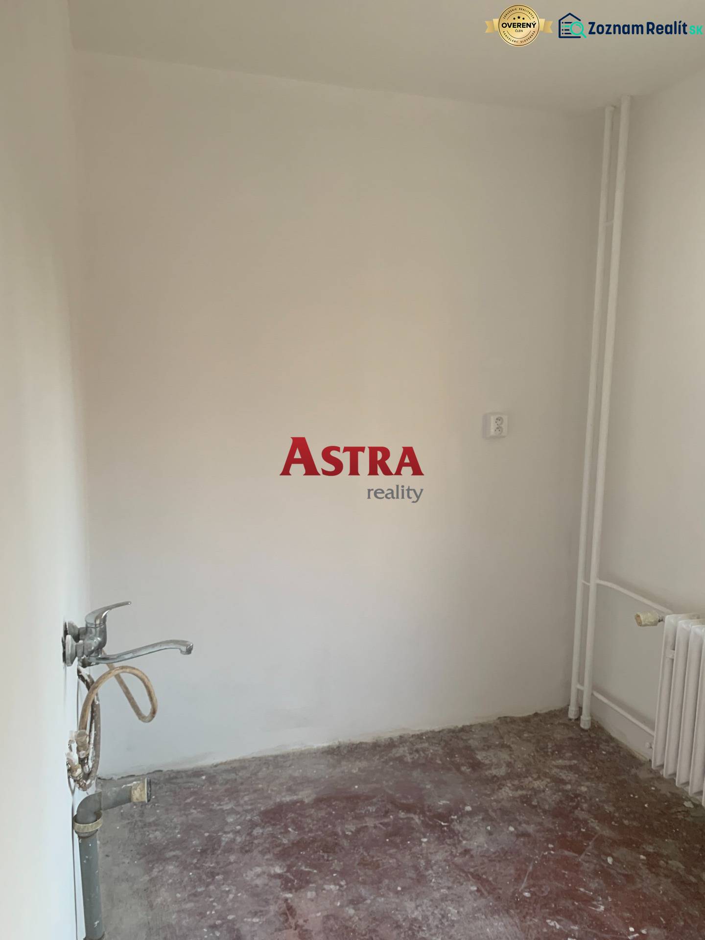 Üres szoba egy kétszobás lakásban padlóburkolat nélkül, mosdóval.