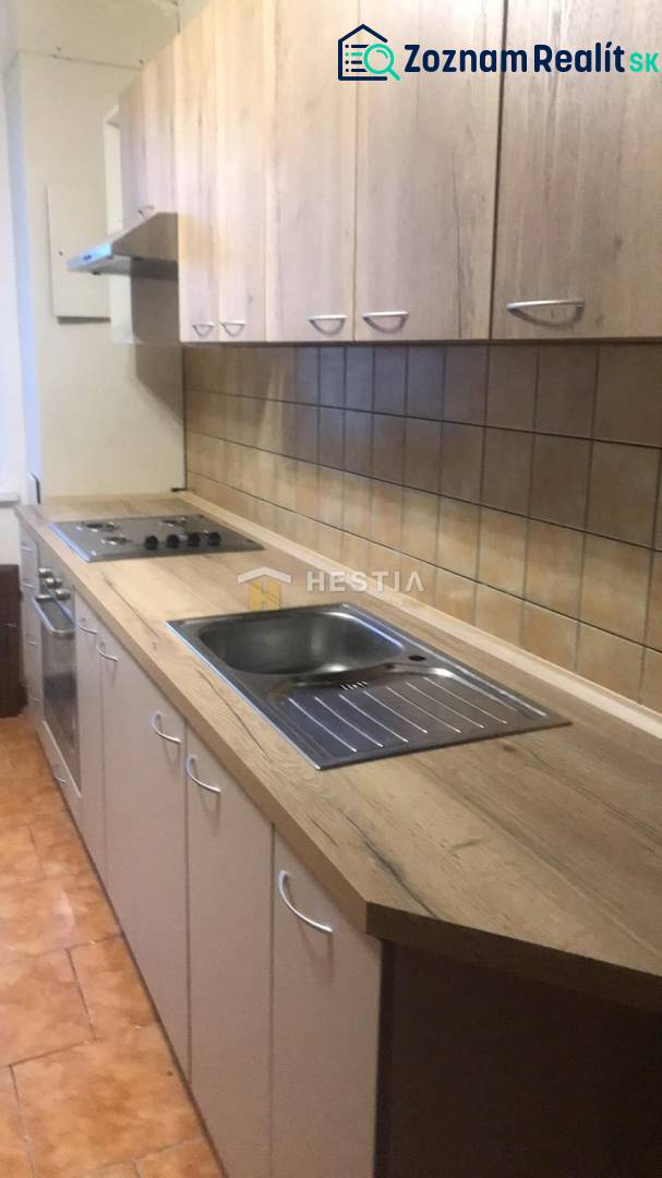 Két szobás lakás konyhája fa dekor padlóval és világos bútorokkal.