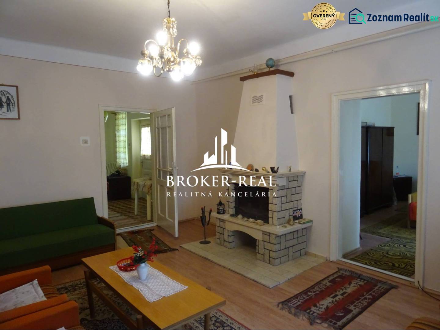 Nappali egy családi házban kandallóval, fa hatású padlóval és csillárral.