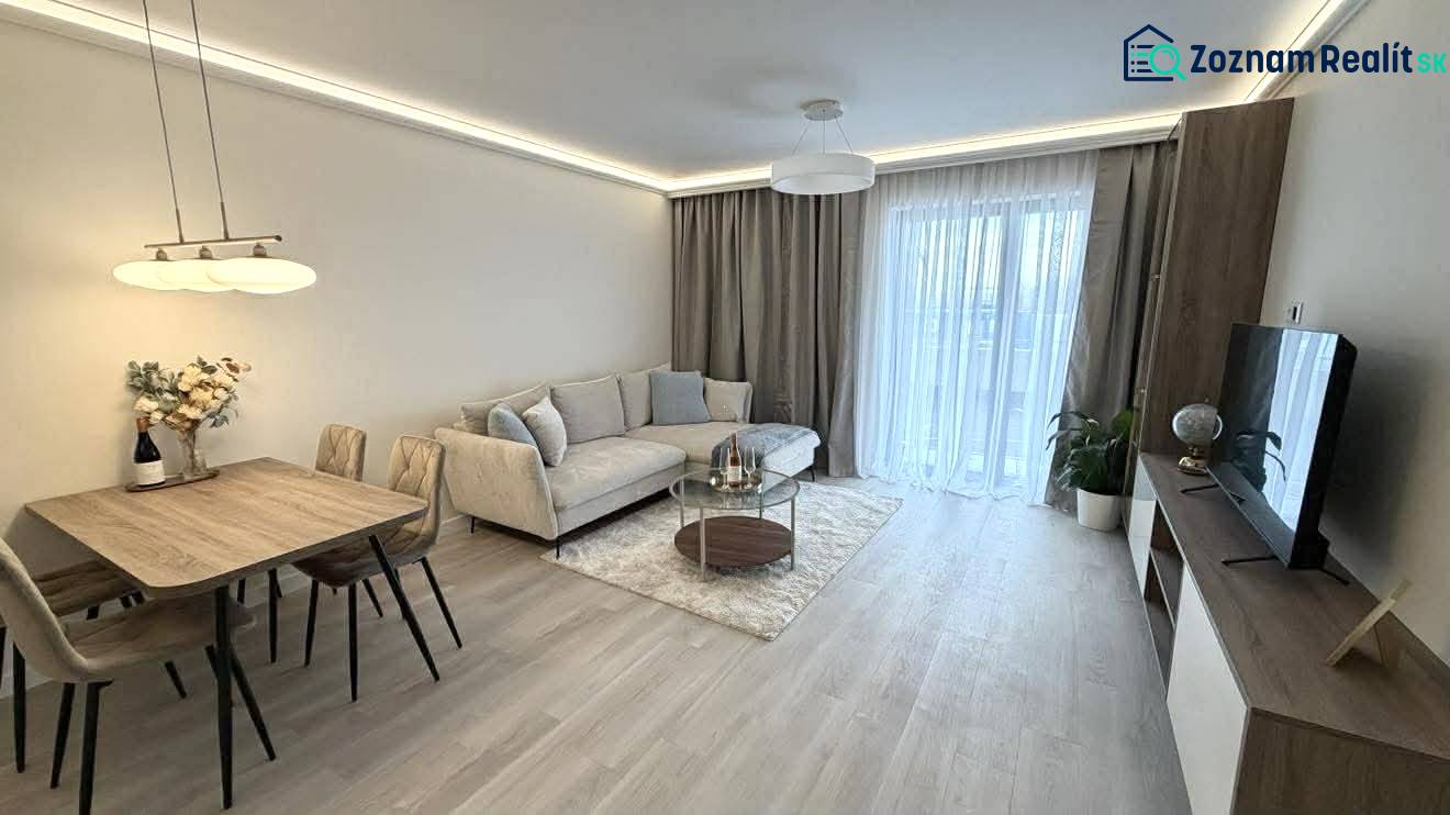 Nappali egy kétszobás lakásban, fa mintázatú padlóval, kanapéval és étkezőasztallal.