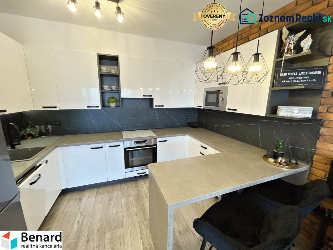 Konyha egy kétszobás lakásban fehér szekrényekkel és fa mintázatú padlóval.