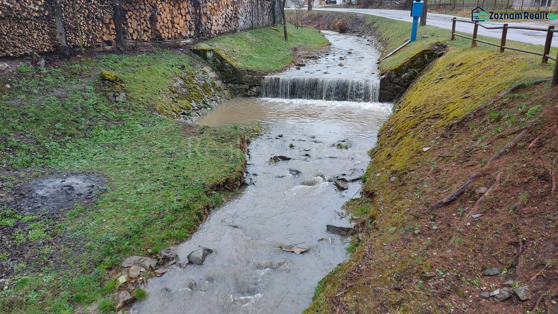 Patak, amely áthalad a puchovi üdülőterületen, a szélén tárolt fával.