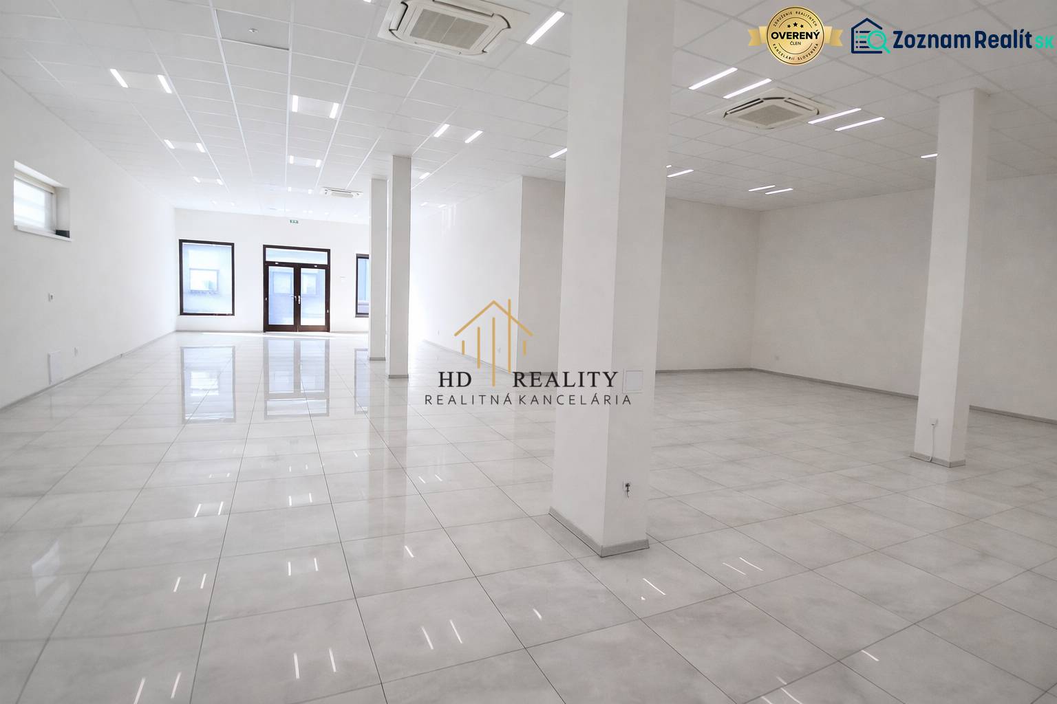 Tágas üzlethelyiségek fehér falakkal és fényes padlóval.