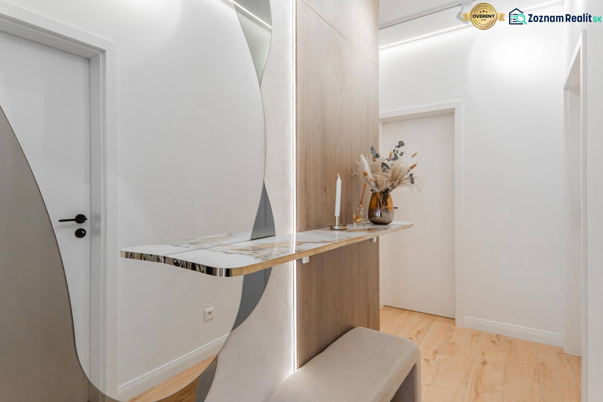 Folyosó egy 3 szobás lakásban minimalista asztallal, tükörrel és fa dekoros padlóval.