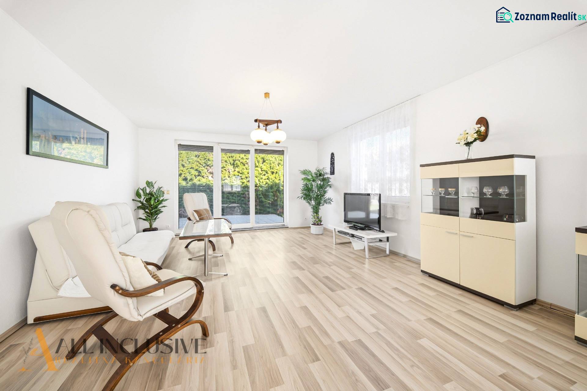 Világos nappali fa mintázatú padlóval, kanapé, fotel és televízió.