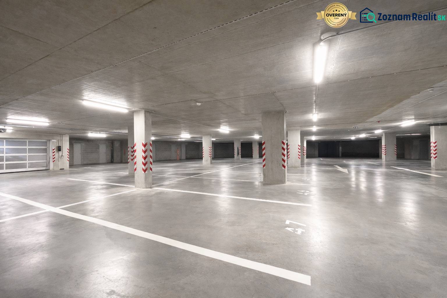 Tágas garázsok kijelölt parkolóhelyekkel, világos világítással, beton oszlopokkal.