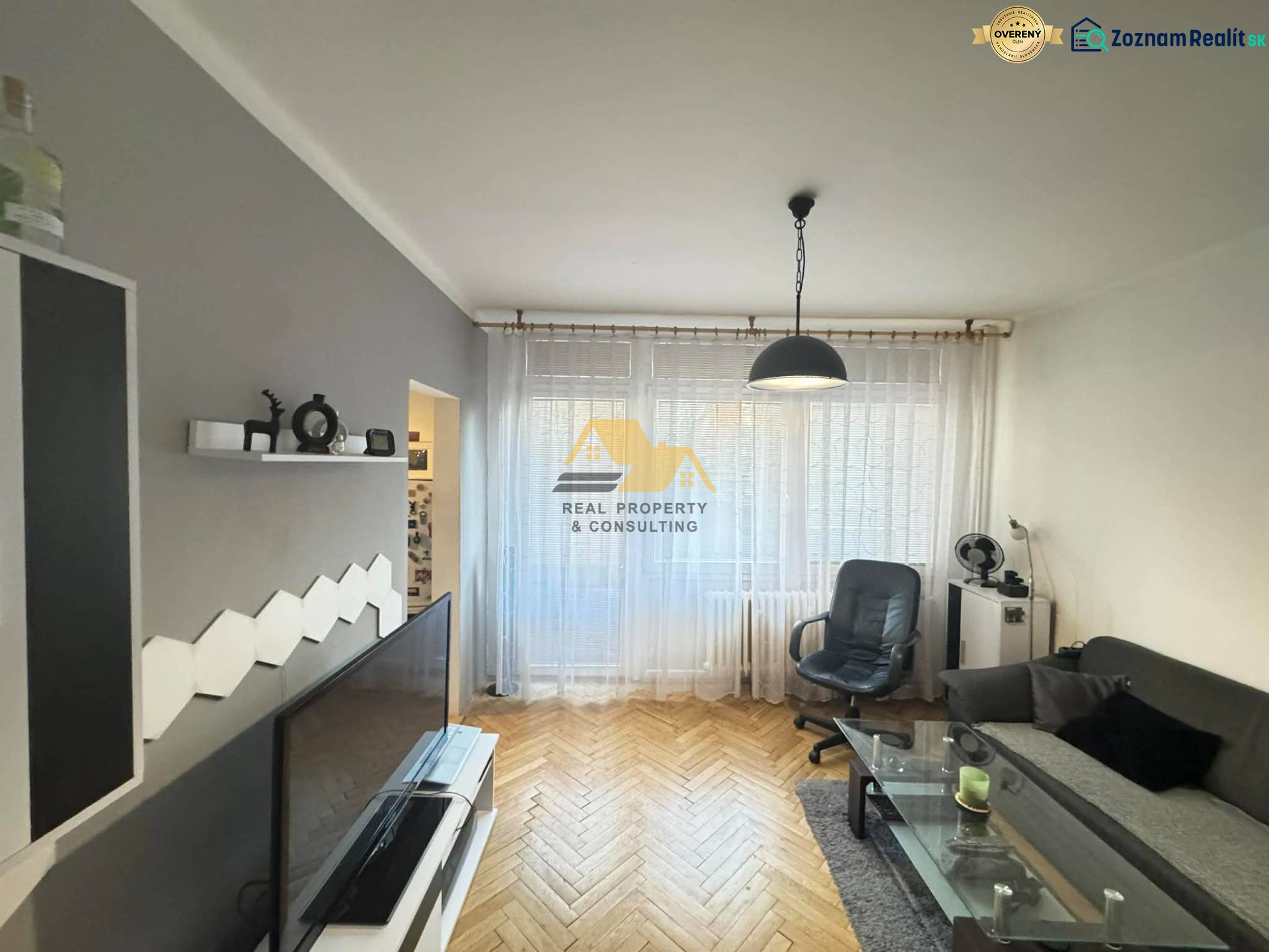 Nappali egy kétszobás lakásban, fa hatású padlóval és stílusos bútorokkal.