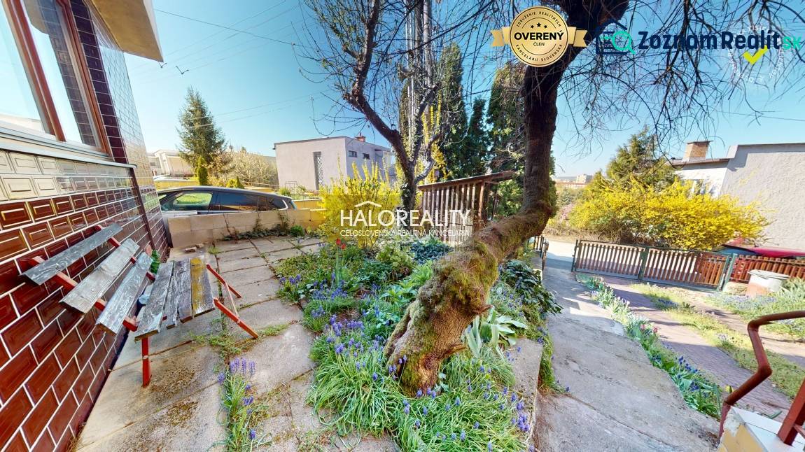 A rimavszombati családi ház előtt van egy kert, egy pad és egy fa.