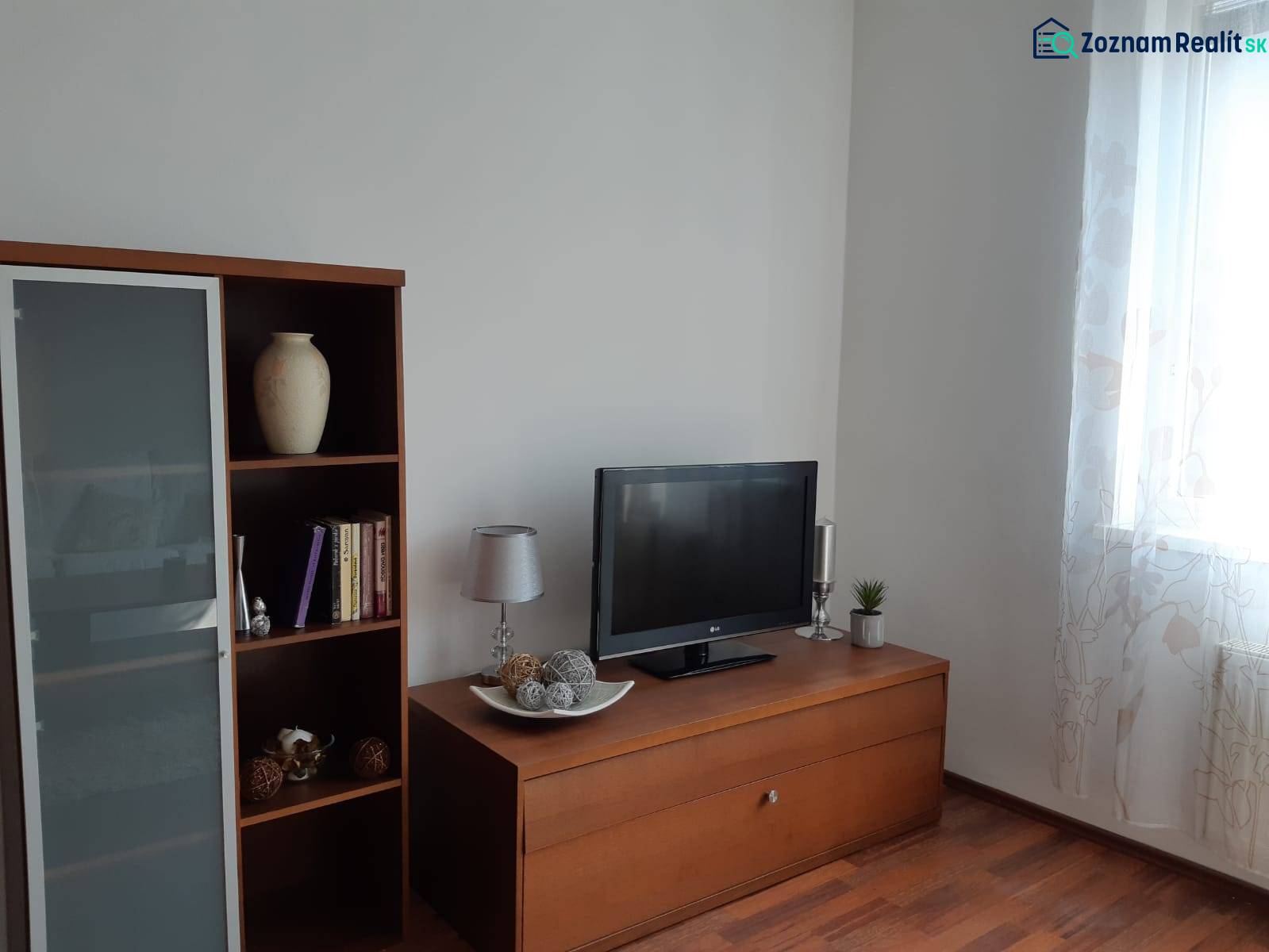 Nappali fa hatású padlóval, könyvespolccal, televízióval és dekoratív tárgyakkal.