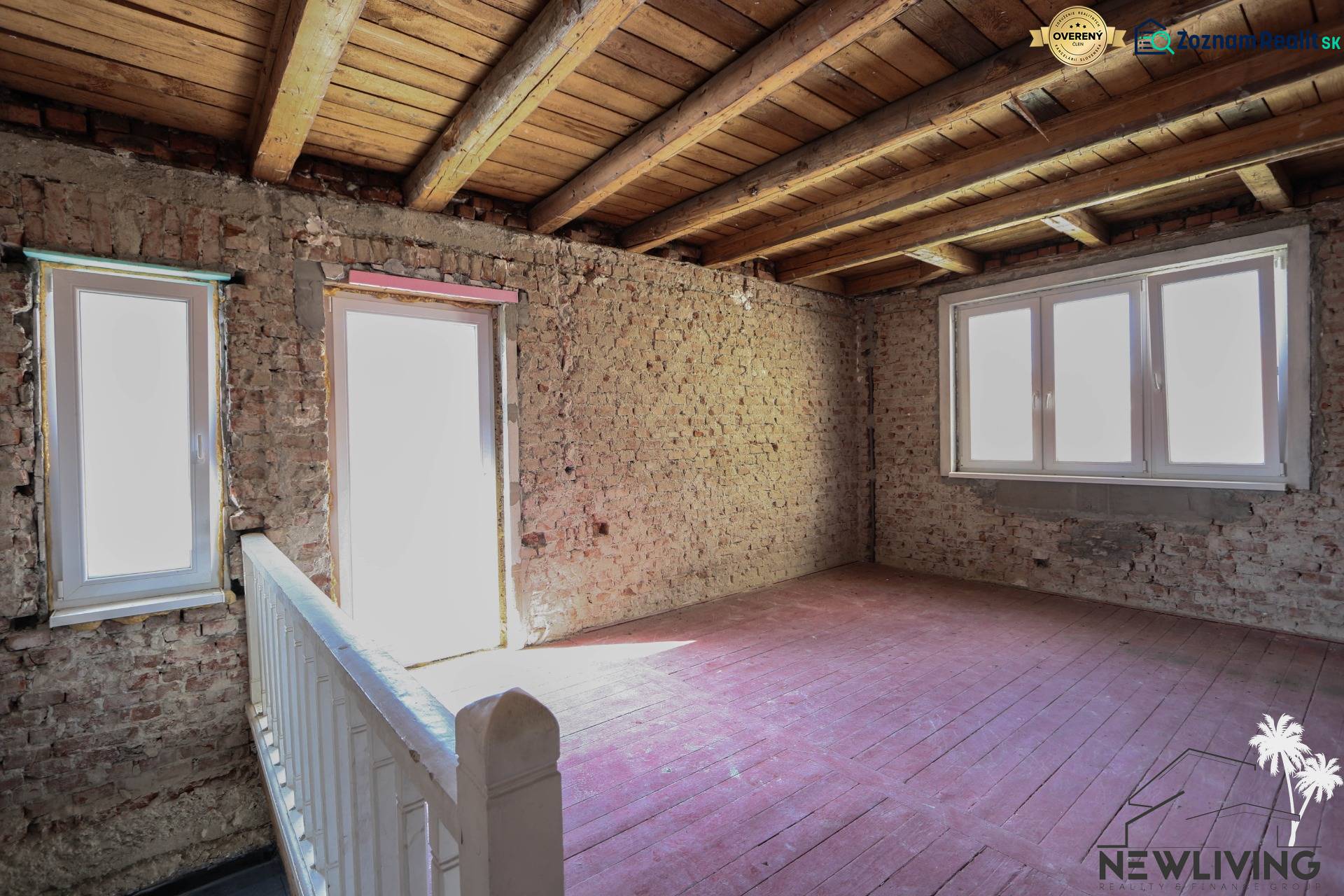 Családi ház belső tere csupasz téglafalakkal, fa mennyezettel és padlóval.