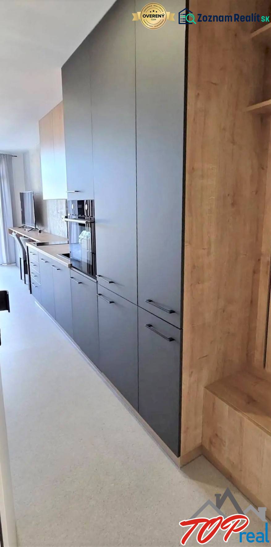 Konyhapult garzonlakásban sötét szekrényekkel és világos, fa mintázatú padlóval.