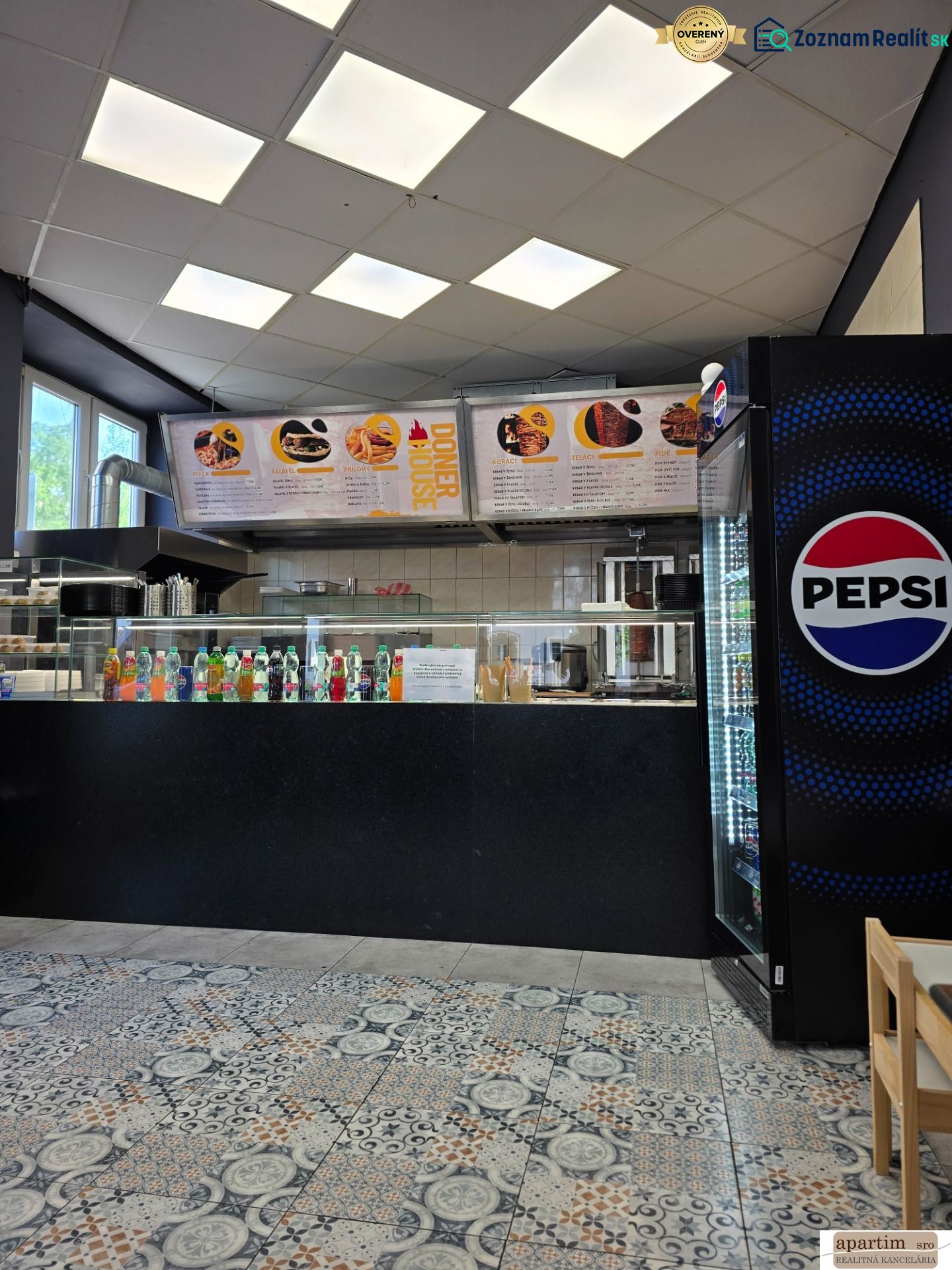 Vendéglátóhelyiség italválasztékkal, Pepsi hűtővel és mintás csempével.