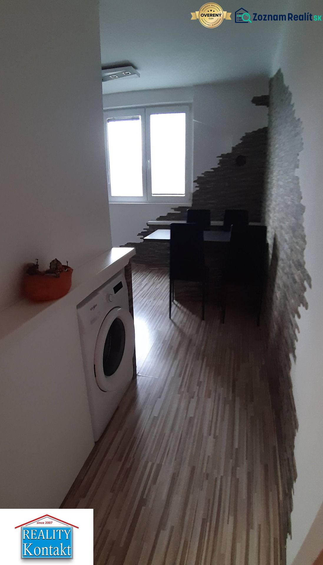 Étkező sarok fa mintás padlóval, mosógéppel és érdekes fallal egy kétszobás lakásban.