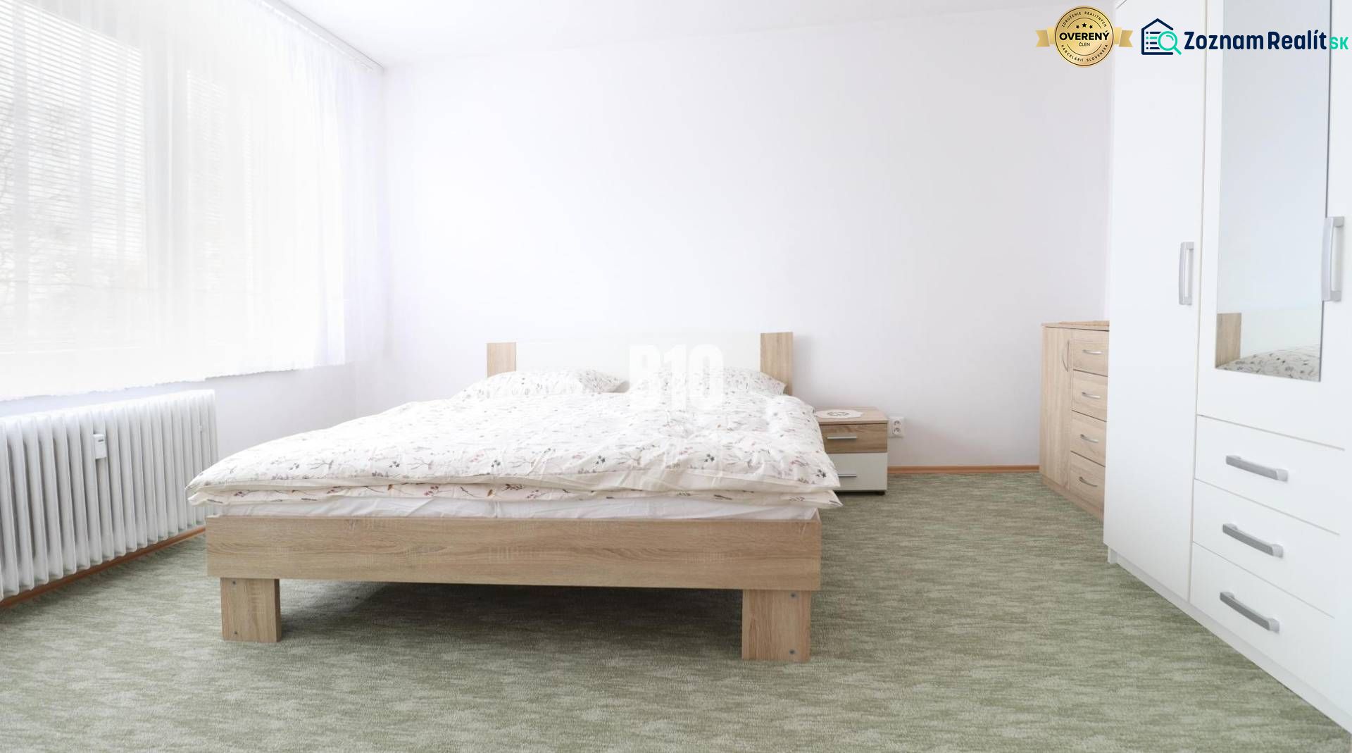 Hálószoba egy háromszobás lakásban, franciaággyal, fehér bútorokkal és szőnyeggel.