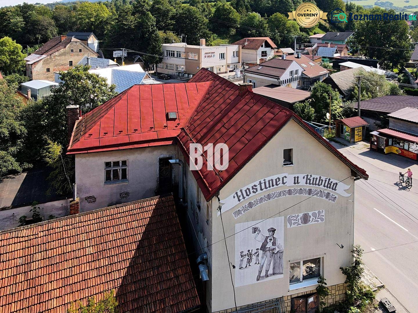 Fogadó Bélán piros tetővel és egy sörös férfit ábrázoló falfestménnyel.