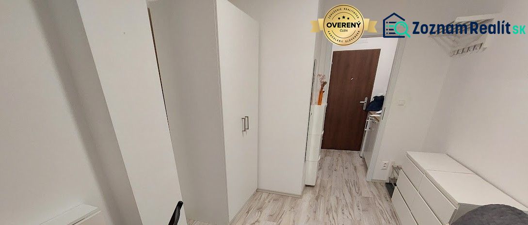Hangulatos garzon fehér bútorokkal és fa mintázatú padlóval.