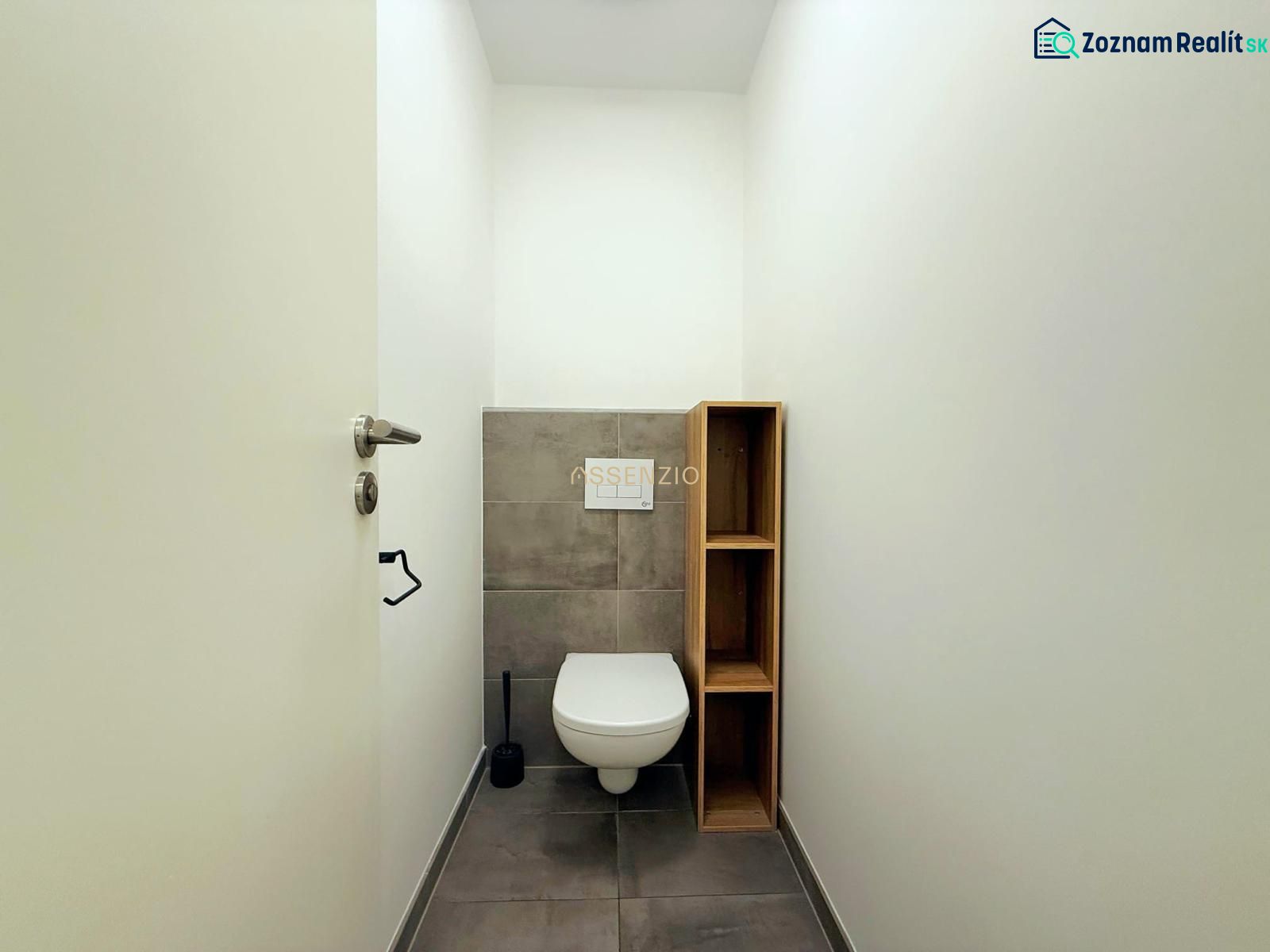 WC szürke csempével és fa polccal egy kétszobás lakásban.