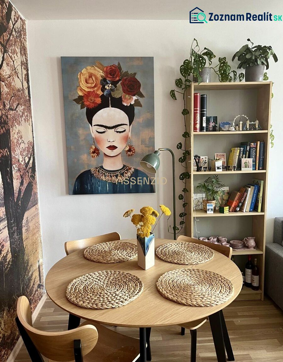 Ebédlő egy két szobás lakásban, képpel, fa asztallal és dekoratív kiegészítőkkel.