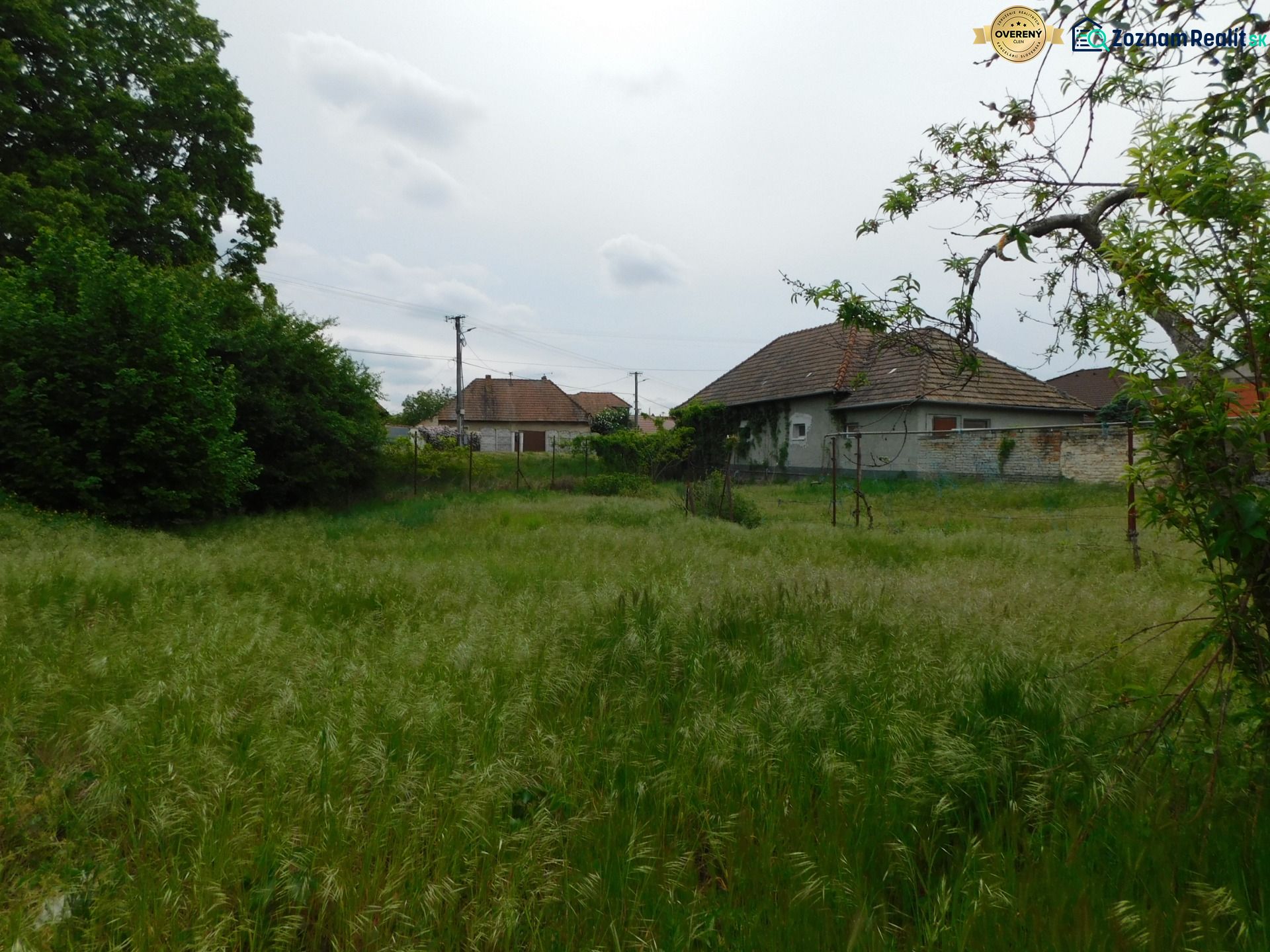 Pozemok na bývanie v Dvoroch nad Žitavou, obklopený zeleňou a vidieckymi domami.