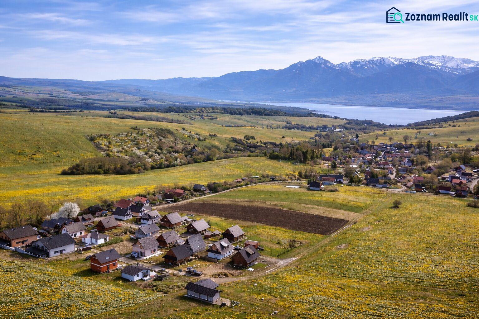 Falusi táj Ižipovce faluban családi házakkal és hegyi panorámával.
