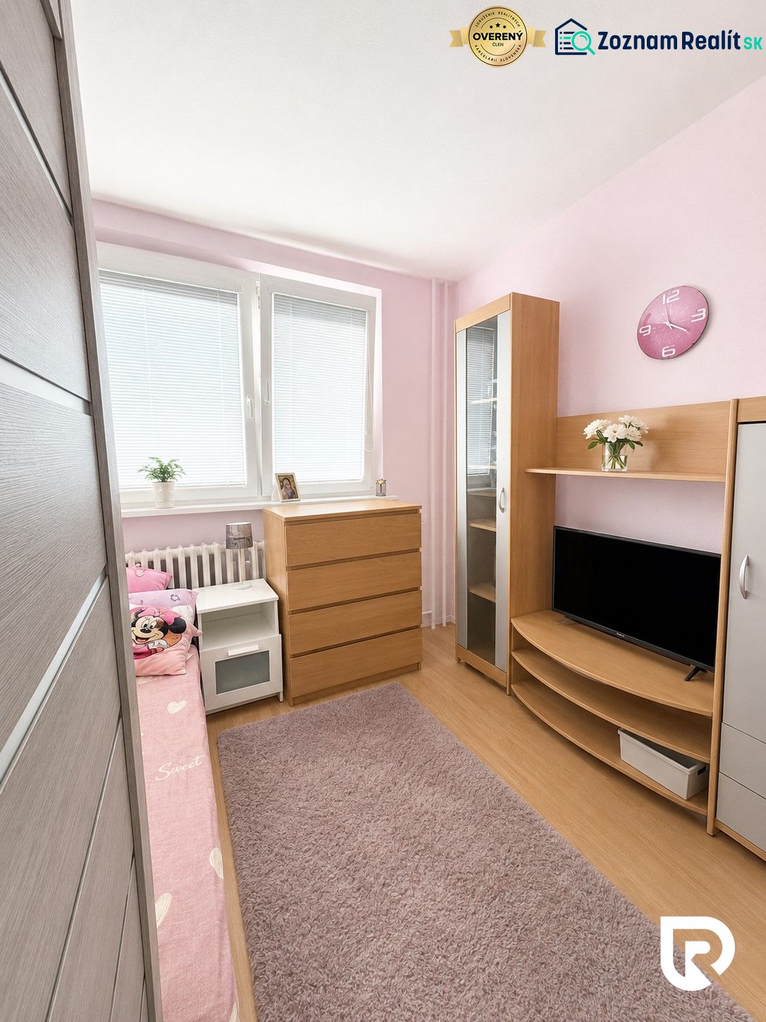 Gyerekszoba fa mintázatú padlóval, rózsaszín falakkal és fa bútorokkal egy háromszobás lakásban.
