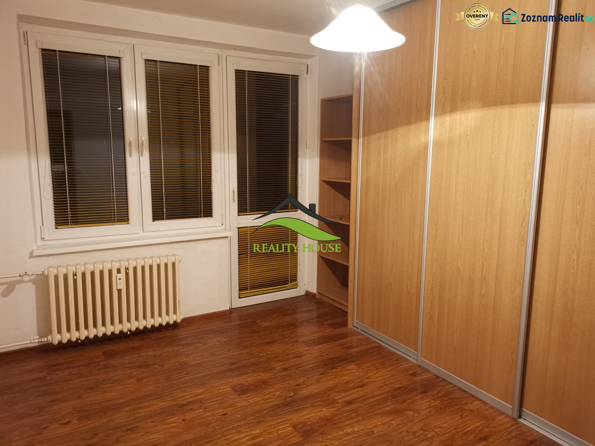 Szoba fa dekor padlóval és nagy beépített szekrénnyel egy háromszobás lakásban.