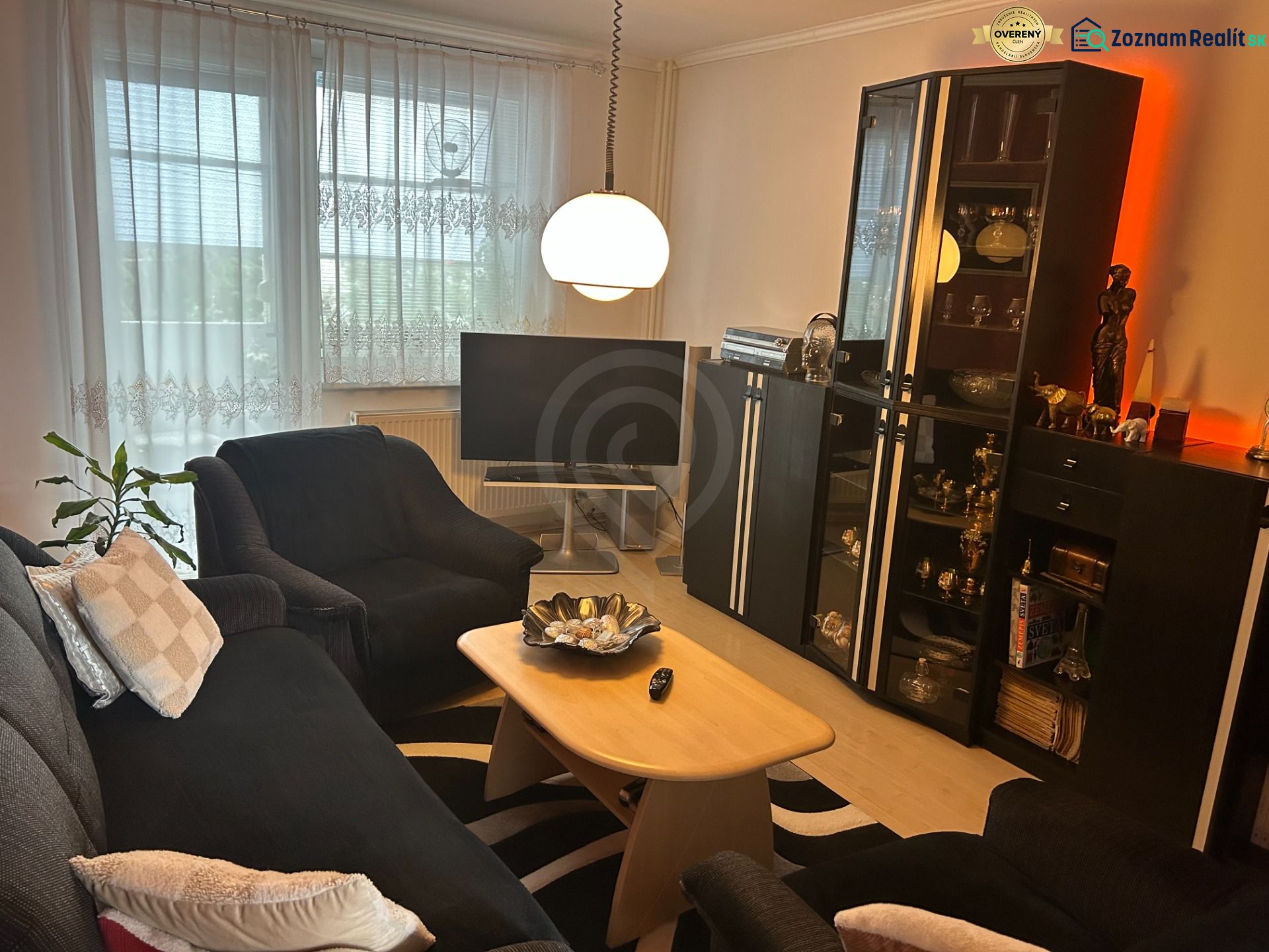 Nappali egy háromszobás lakásban kényelmes ülőhellyel és állólámpával.