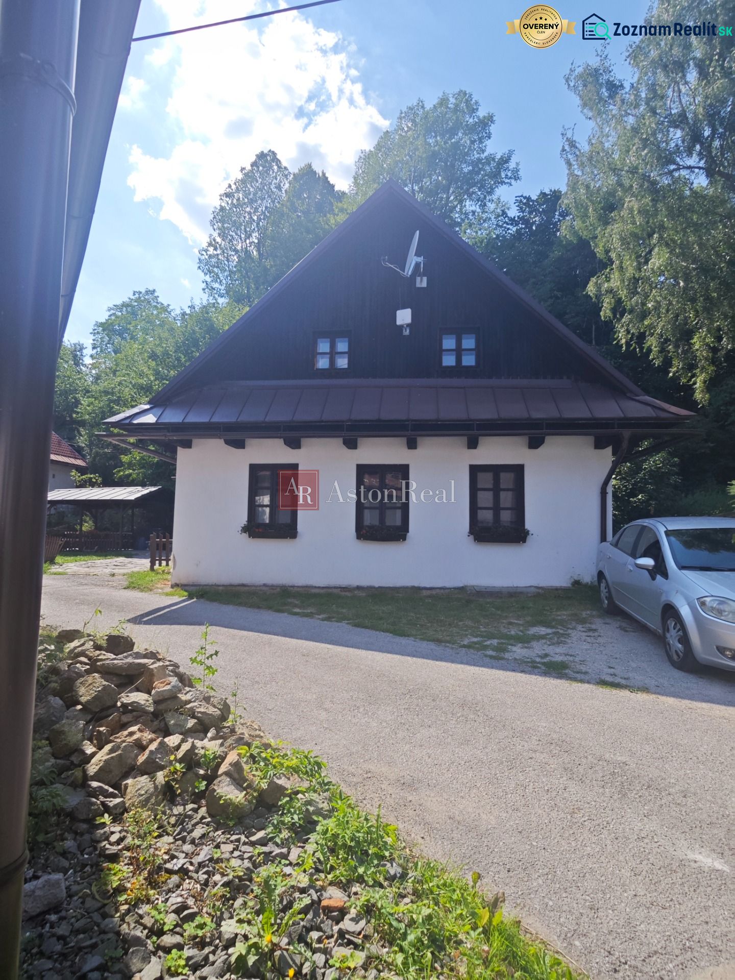 Ház Spania Dolinában fehér homlokzattal és műholdas antennával, zölddel körülvéve.