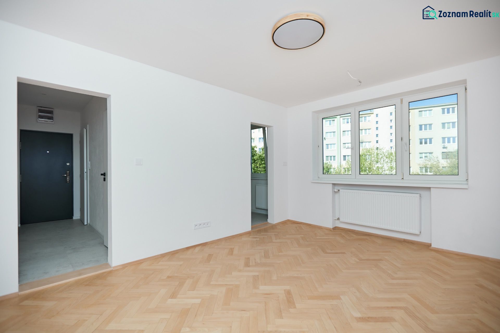 Lakás fa dekor padlóval, fehér falakkal és nagy ablakokkal.