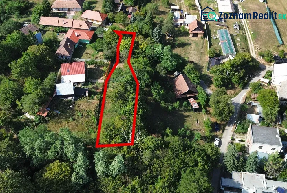 Légi felvétel a Kolačnában található kertekről, amelyeket házak és zöldterületek vesznek körül.