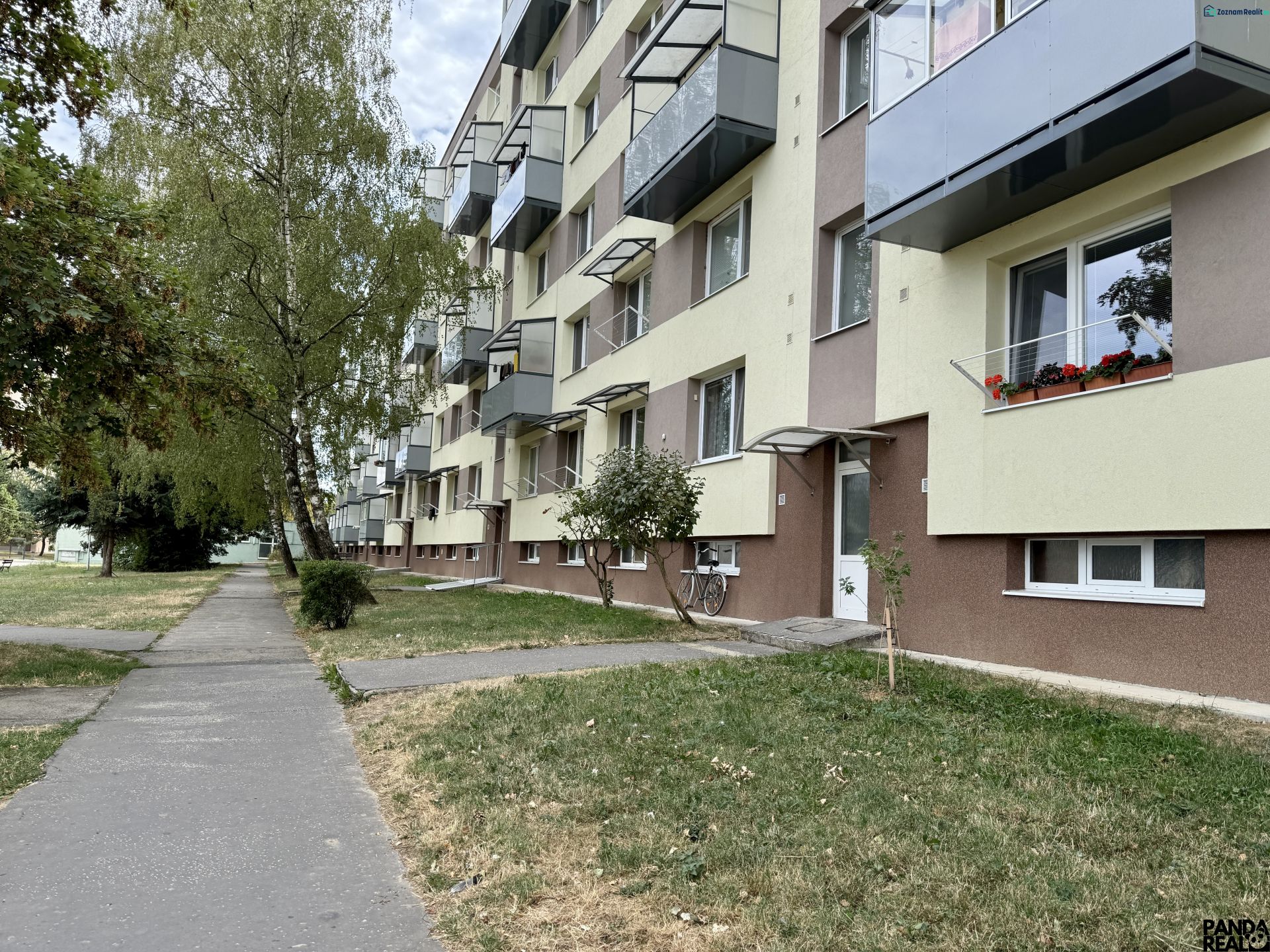 Lakóház zöldterülettel és járdával, Topoľčanyban található, fákkal körülvéve.